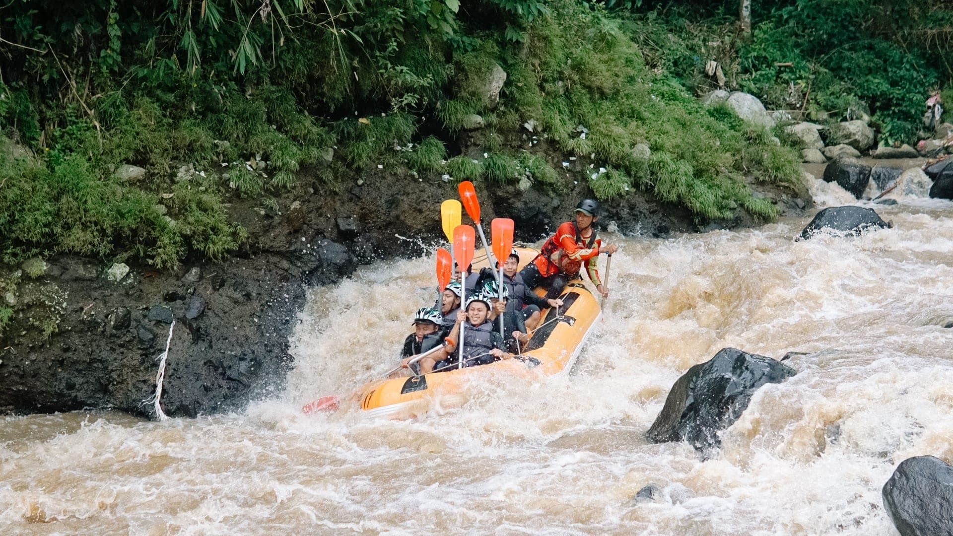 Whitewater rafting near Ubud — orange raft through tropical river rapids