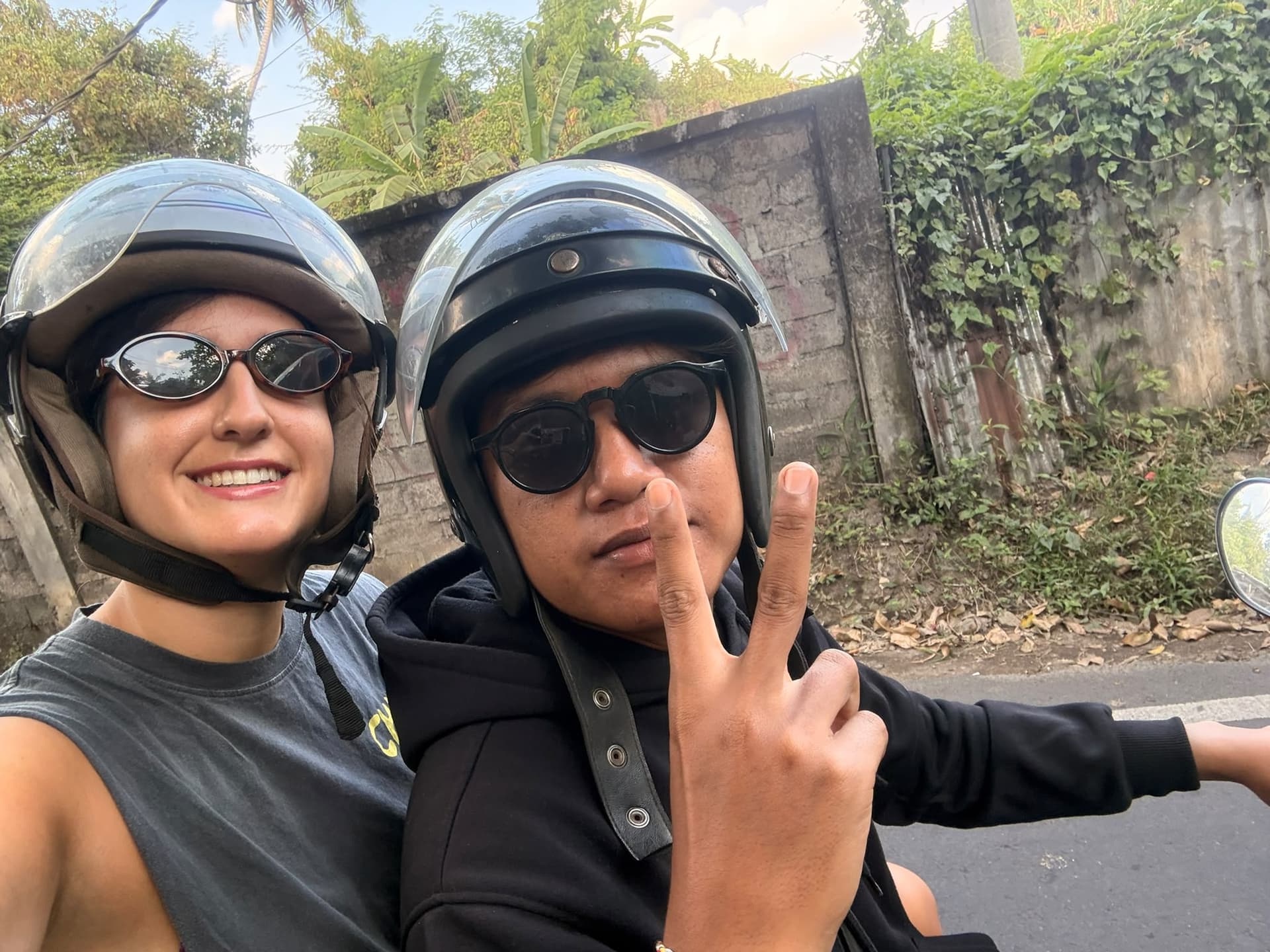 Smiling guests wearing helmets on a guided Bali motorbike traveling trip