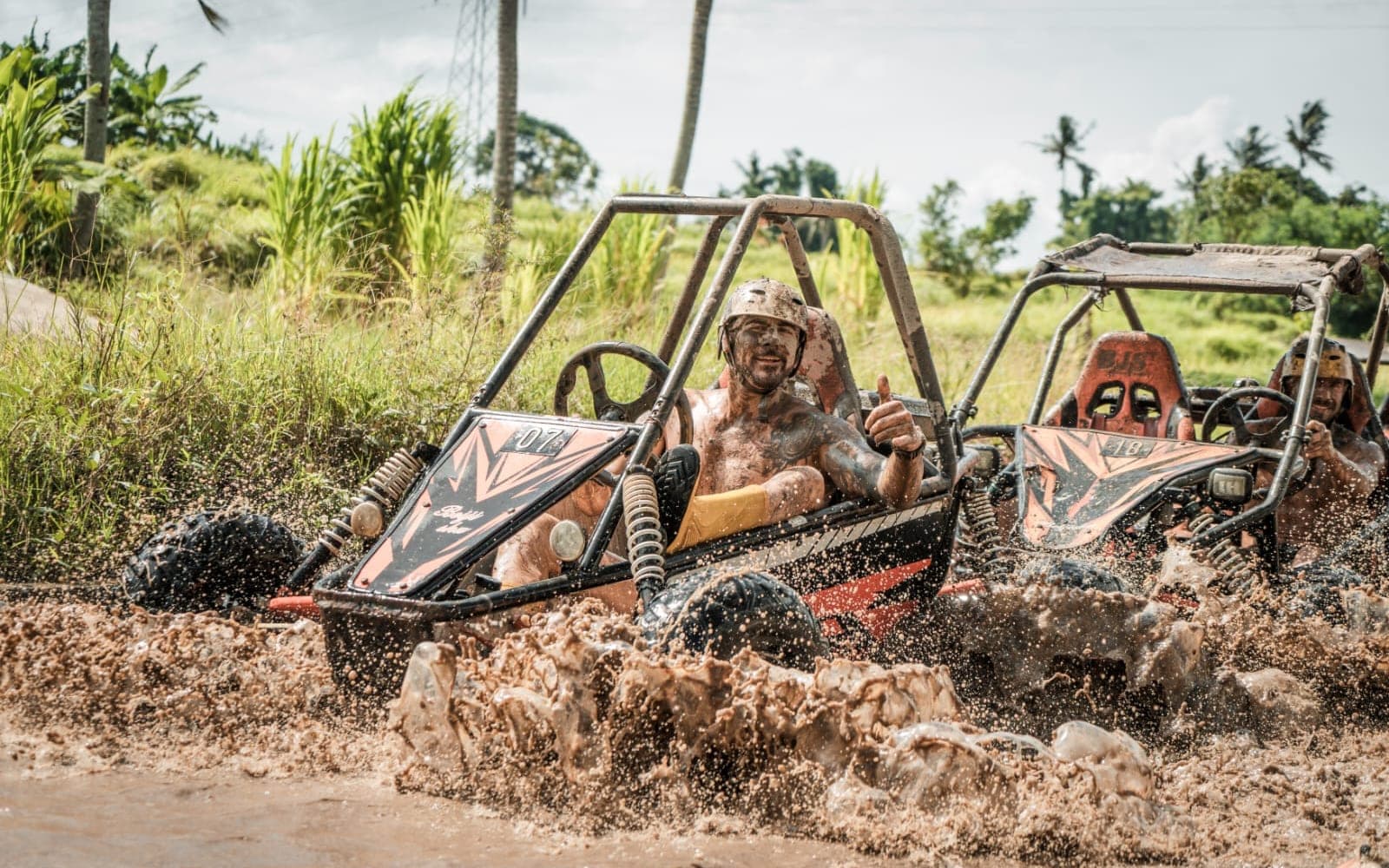 UTV buggy driver giving a thumbs-up through mud spray