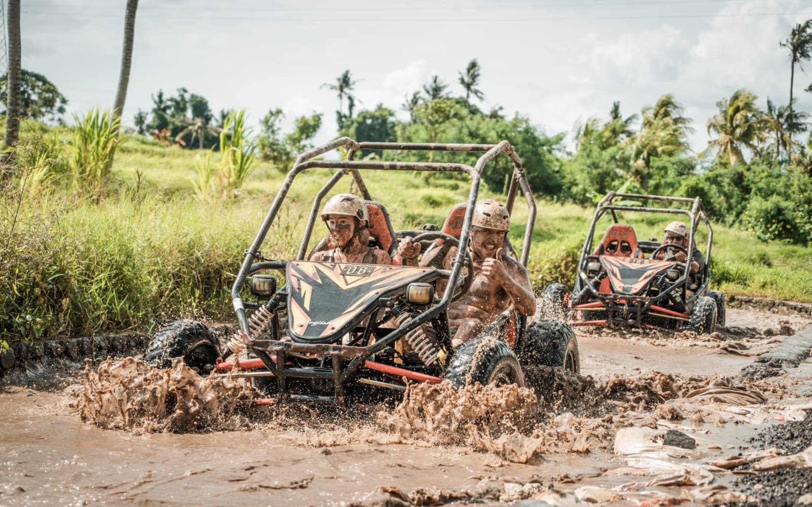 Two UTV buggies splashing through a muddy ricefield track in Bali