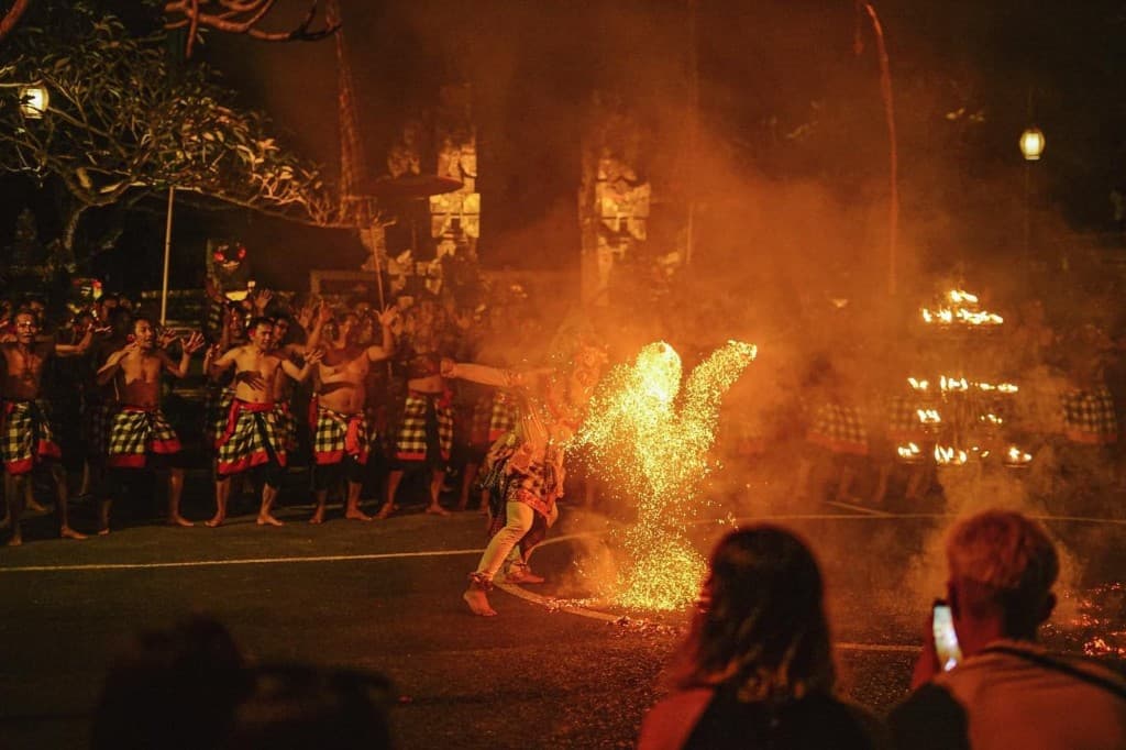 Kecak chorus and a dancer kicking fire sparks in front of the temple gate at Kutuh Kaja